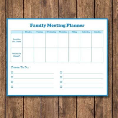 A family meeting planner dry-erase board with columns for each day of the week and dedicated sections for activities, dinner plans, and chores sits on a wooden surface—perfect for keeping everyone organized.