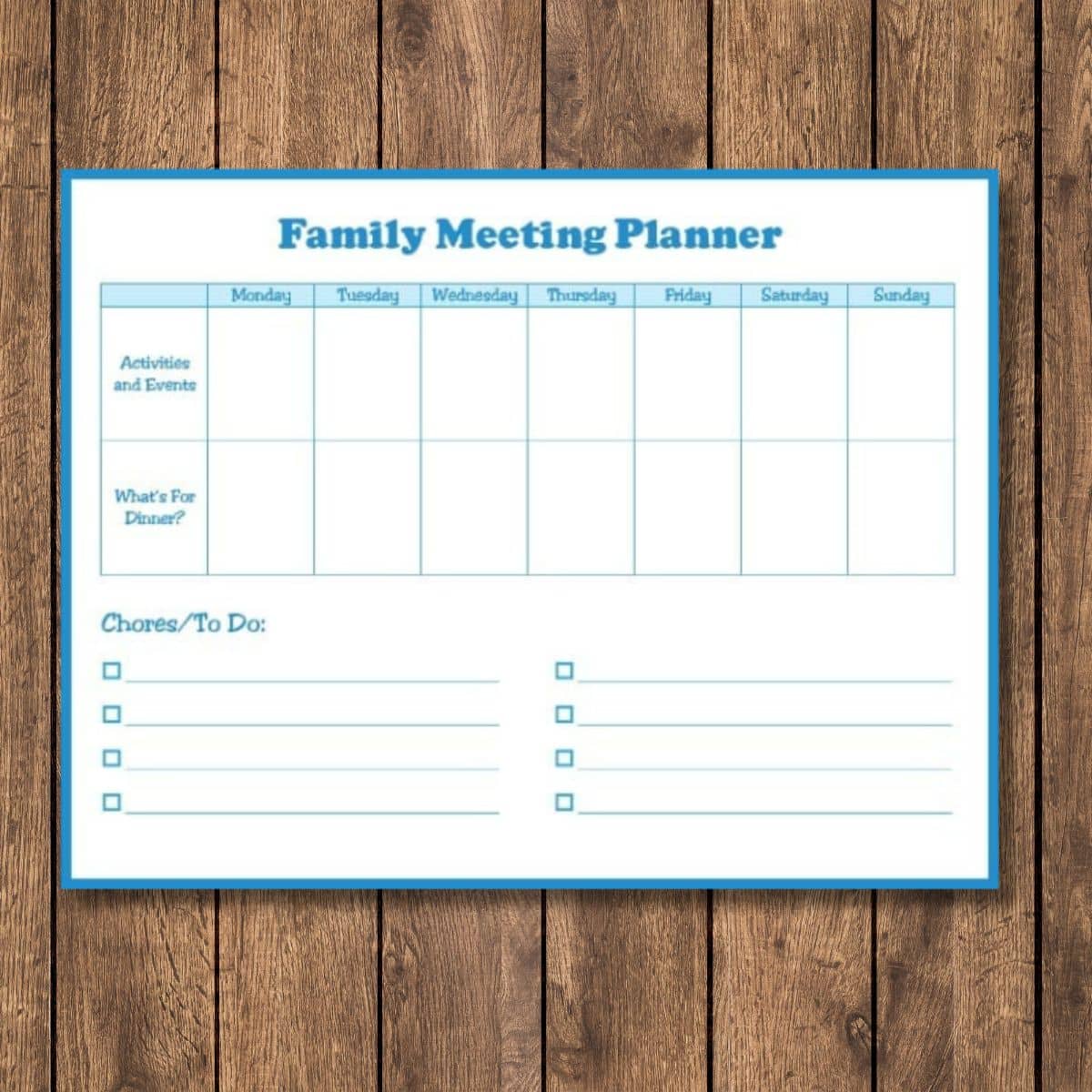 A family meeting planner dry-erase board with columns for each day of the week and dedicated sections for activities, dinner plans, and chores sits on a wooden surface—perfect for keeping everyone organized.