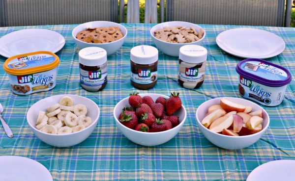 fruit and crackers in white bowls and jif whips and spreads on a table as end of summer Snackation Snacks
