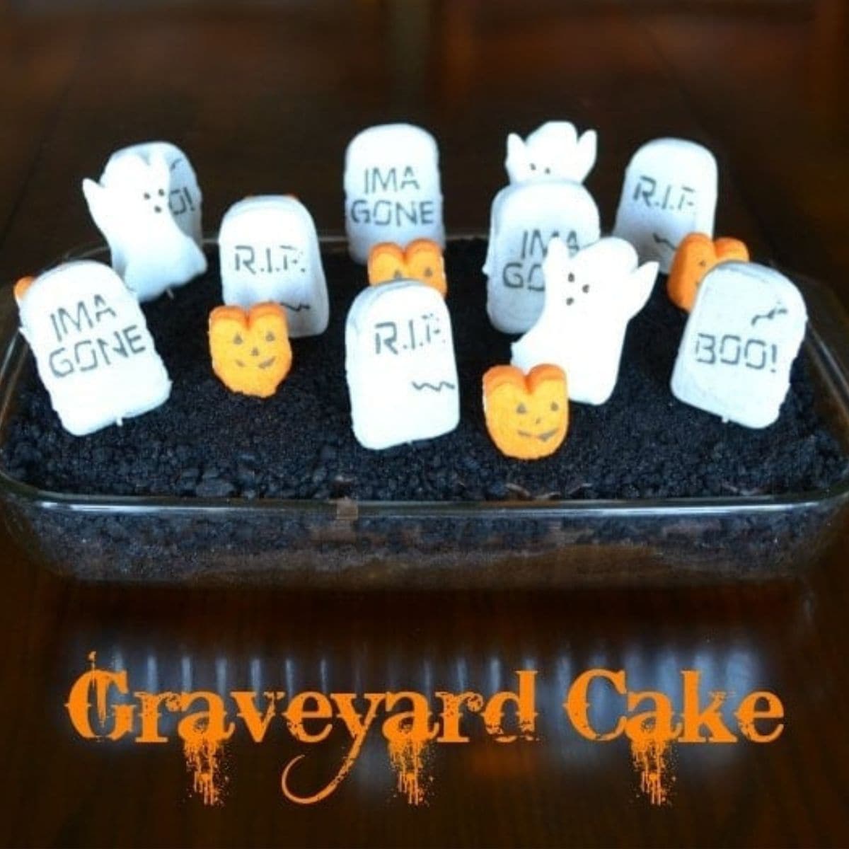 A rectangular graveyard cake topped with cookie crumb "soil," marshmallow ghosts, candy pumpkins, and tombstones labeled "R.I.P.," "I'M A GONE," and "BOO!" Text reads "Graveyard Cake.