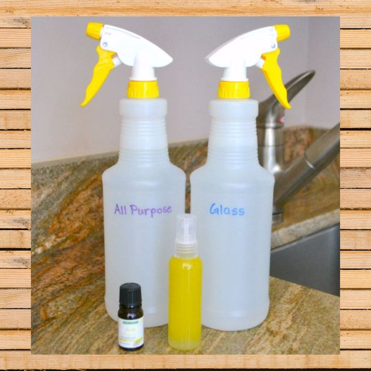 Two labeled spray bottles, one marked "All Purpose" and the other "Glass," stand on a kitchen counter alongside a small spray bottle and an essential oil bottle—perfect for showcasing homemade cleaning products.