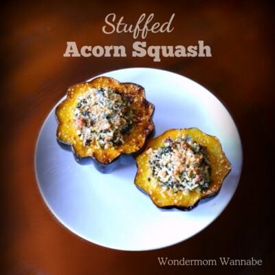 Two halves of stuffed acorn squash with a crispy breadcrumb topping sit on a white plate, featuring the text “Stuffed Acorn Squash” and “Wondermom Wannabe.”.