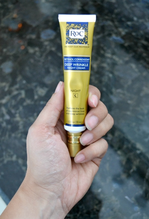 a hand holding a bottle of ROC nighttime cream