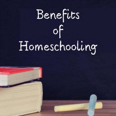 A stack of books and two pieces of chalk sit on a table, with the blackboard in the background highlighting the benefits of homeschooling.