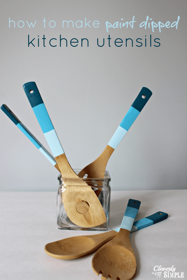wooden utensils with painted handles in a glass jar on a gray background with title text reading how to make paint dipped kitchen utensils