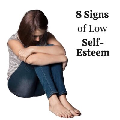 A person sits on the floor hugging their knees with head down beside the text "8 Signs of Low Self-Esteem," visually representing common signs of low self esteem.