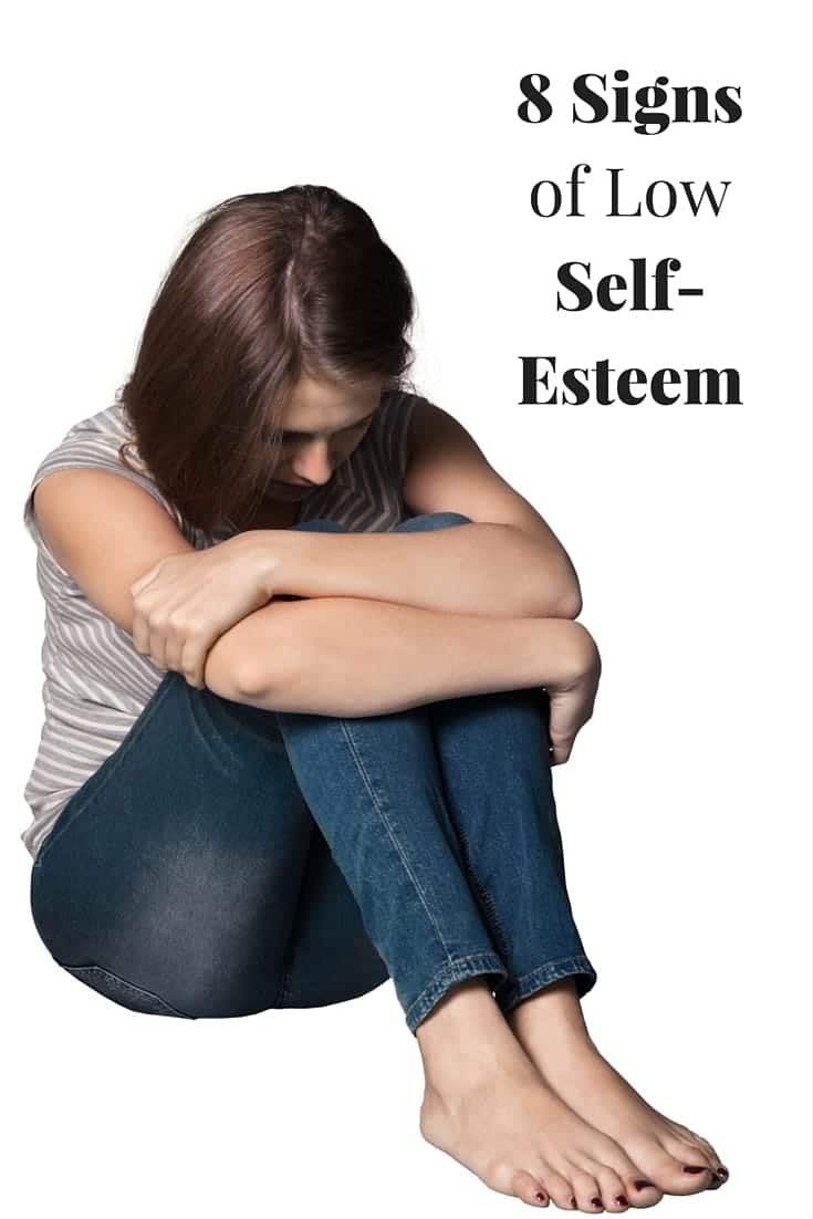 a girl sitting with her head down with title text reading 8 Signs of Low Self Esteem