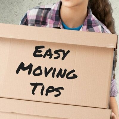 A person holds cardboard boxes, with “Easy Moving Tips” boldly printed on the front box, ready to share practical advice for a smoother move.