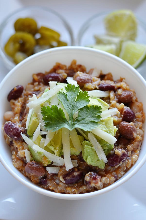 Quinoa-Bean-Chili in a white bowl with a galss bowl of lemons on  a white background 