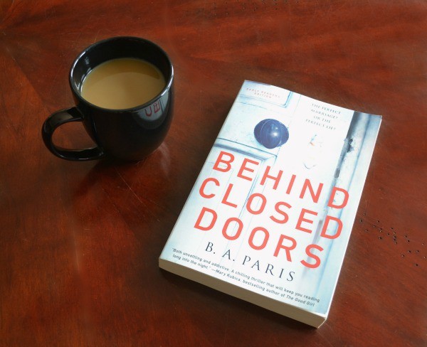 Start Behind Closed Doors book next to a cup of coffee on a brown table