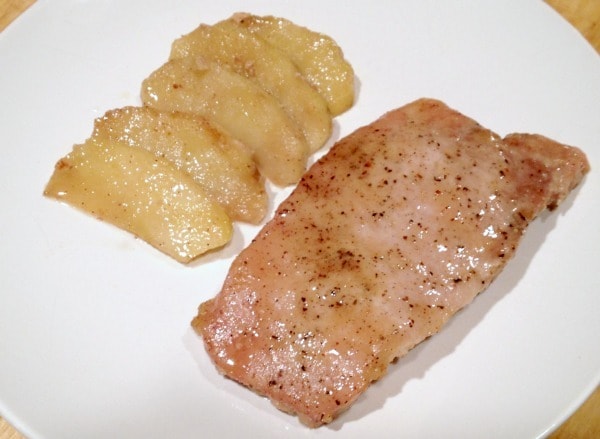 baked pork chop and apple slices on a white plate