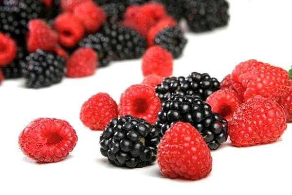 Raspberries and blackberries on white background