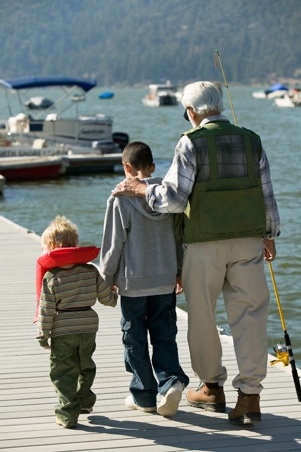 a grandpa and his grandkids walking on a boat dock on a lake