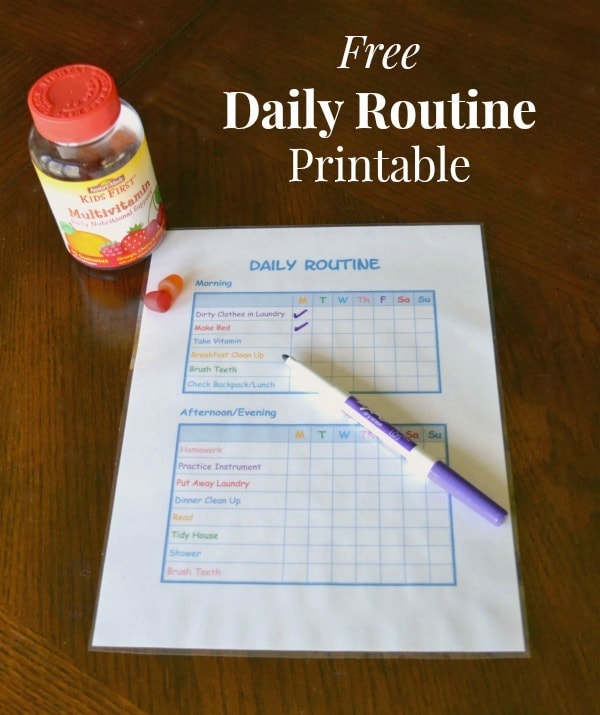 a daily routine printable for kids with a pen on it and vitamins on a brown table with title text reading Free Daily Routine Printable