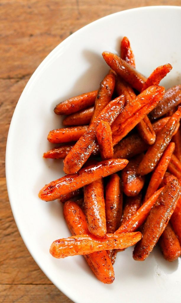 Honey Glazed Oven Roasted Carrots in a white dish on a brown table