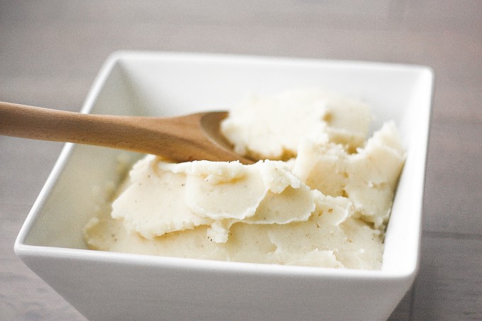 Healthy Mashed Potatoes in a white dish with a wooden spoon in it