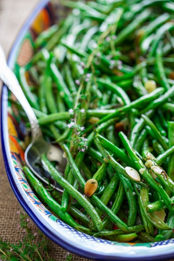 Roasted Green Beans with Almonds in a blue and white bowl with a spoon in it