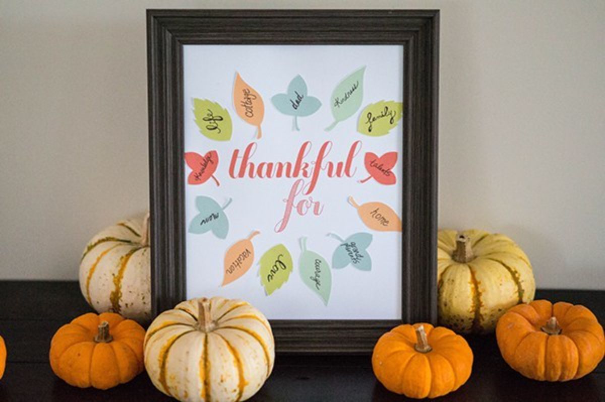 Easy thanksgiving decor ideas: A framed sign adorned with pumpkins and leaves.