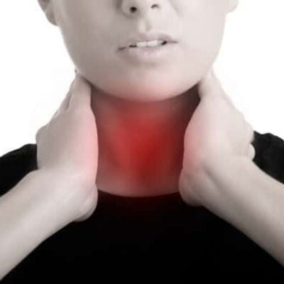 A person holds their neck with both hands, with a red area indicating pain or discomfort in the throat, possibly seeking natural sore throat remedies for relief.
