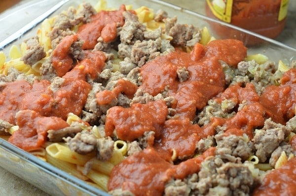 pasta, cheese, meat mixture, sauce in a glass baking dish
