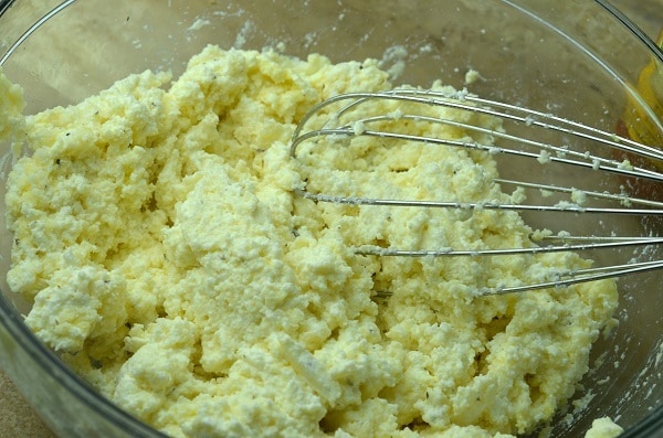 cheeses, egg and seasonings being whisked in a glass bowl