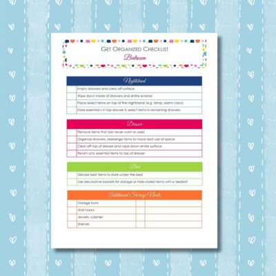A printed get organized checklist for your bedroom, featuring organizing tasks for the nightstand, dresser, bed, and storage needs—all set on a blue background with heart patterns.