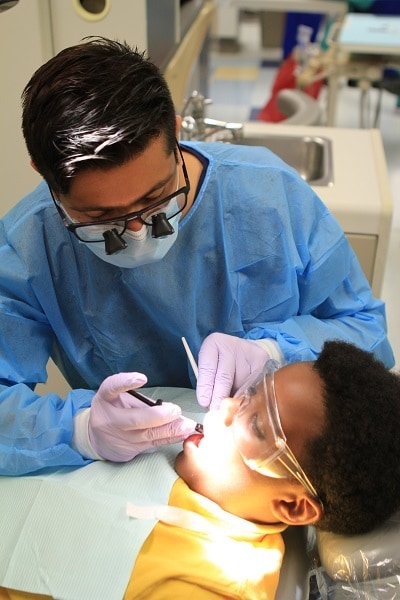 a dentist working on a boy's teeth for Give Kids A Smile