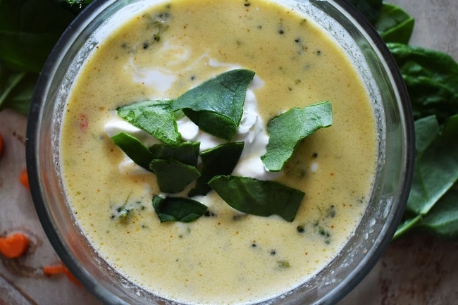 a bowl of broccoli cheese soup topped with green leaves
