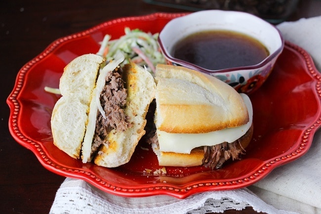 a french dip sandwich on a red plate with sauce in a bowl