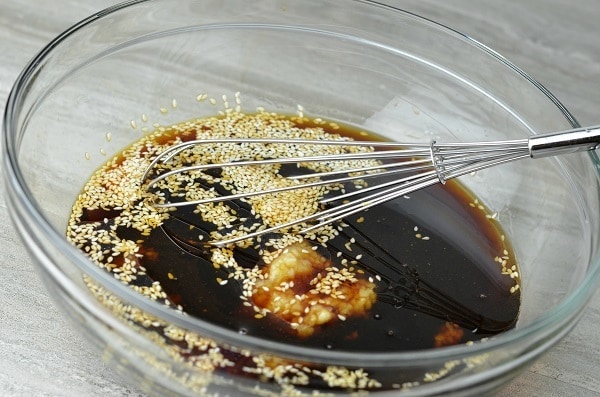 marinade with sesame seeds in it, in a glass bowl on a table