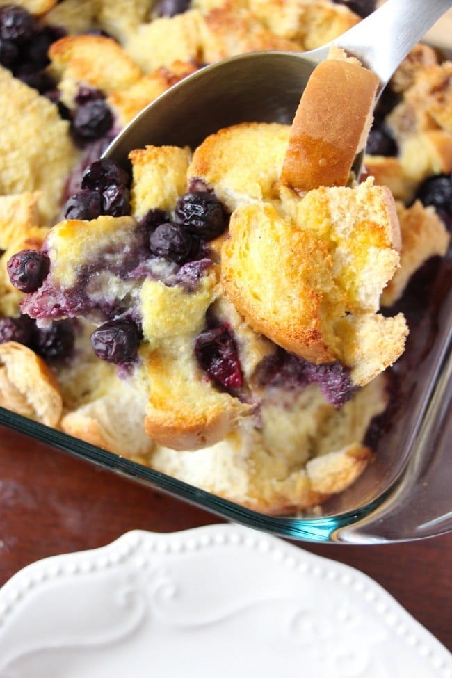 blueberry french toast casserole with a spoon in it in a glass baking dish