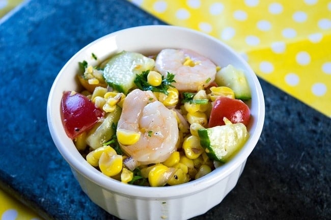 grilled corn salad in a white bowl on a blue cloth on a yellow and white polka dot paper
