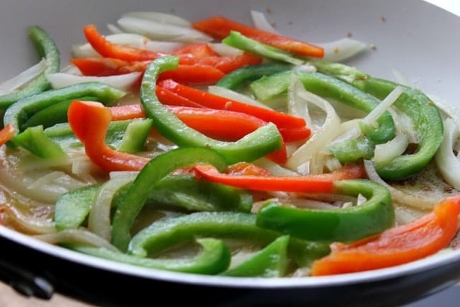 sliced onions and bellpeppers cooking in a skillet
