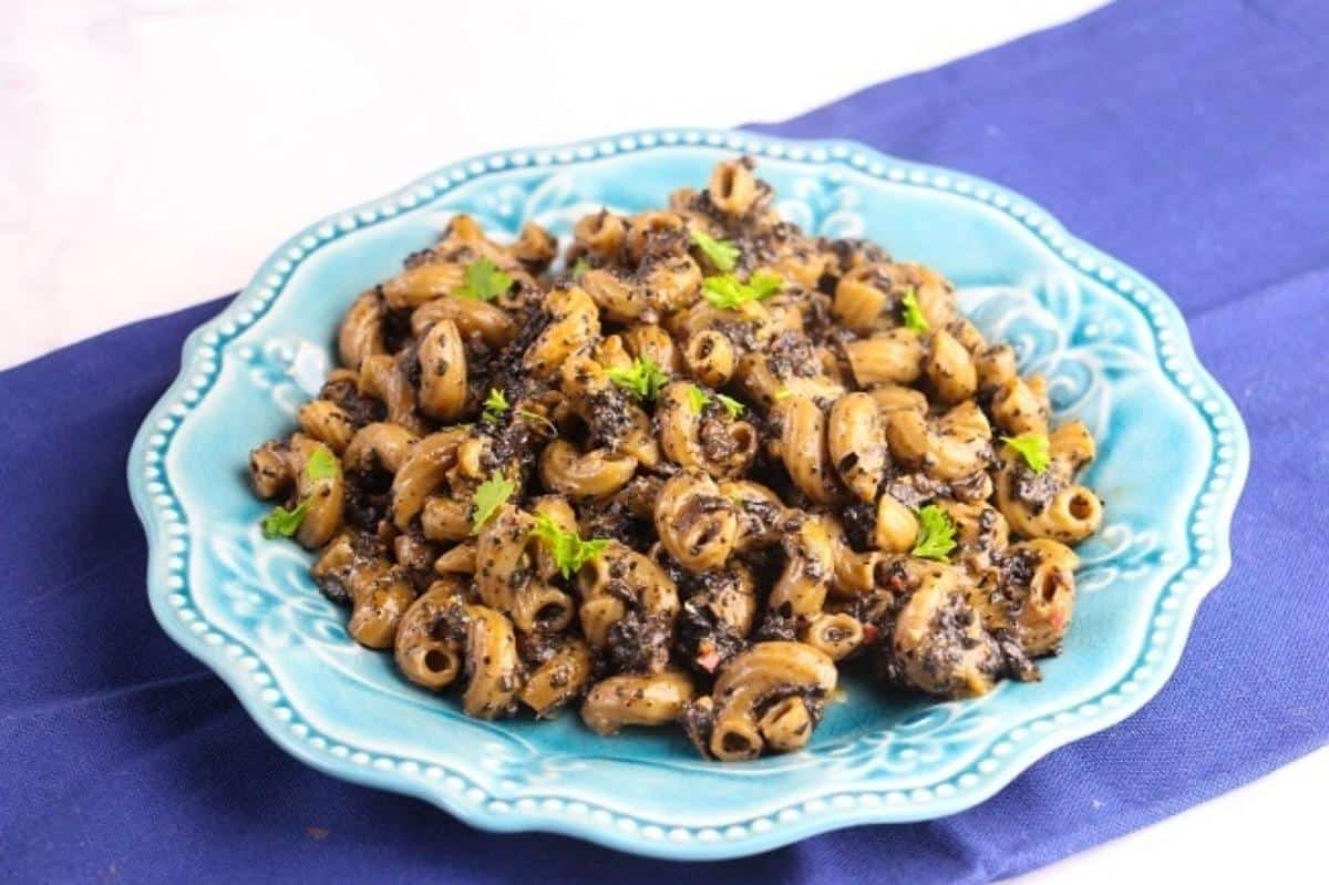 A delicious instant pot mushroom pasta dish garnished with parsley on a blue plate on a blue cloth.