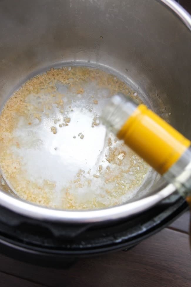 white wine being added to garlic and butter in an instant pot