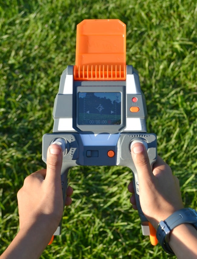 a kid holding the remote for the nerf drone with grass underneath them