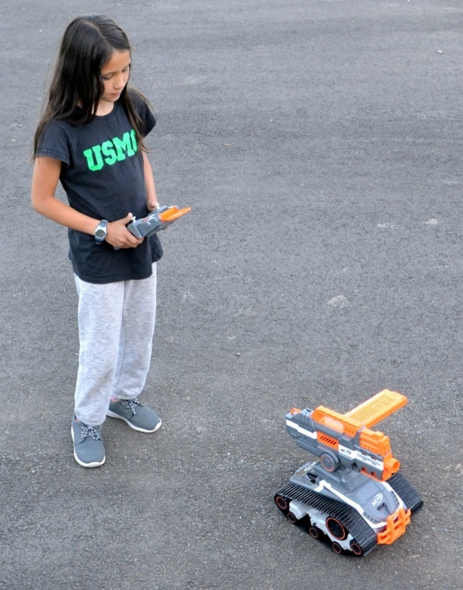 a girl using the remote of the nerf drone outside on the asphalt