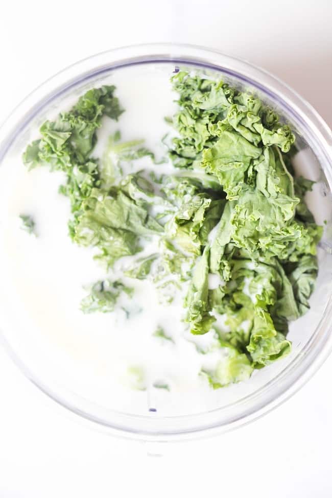 overhead view of kale and milk in a blending cup