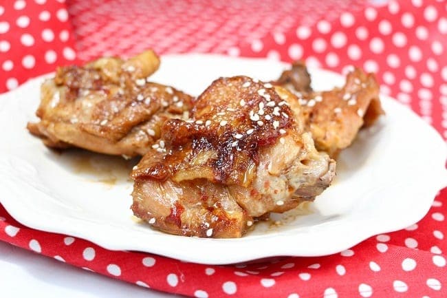 honey garlic chicken on a white plate on a red and white polka dot cloth