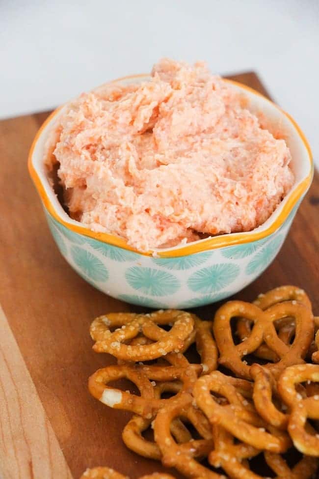 smoked salmon dip in a bowl next to pretzels on a wood board