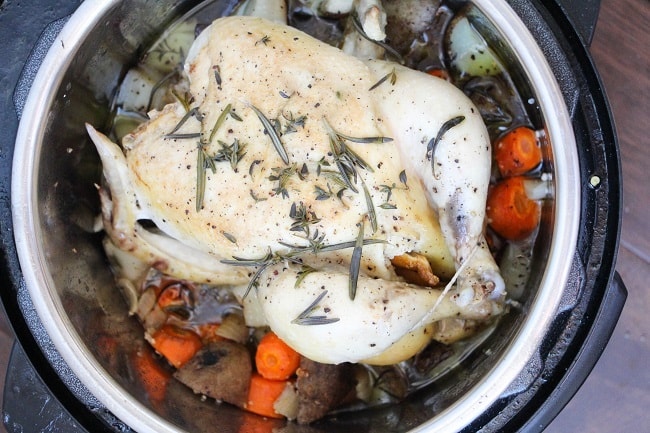 a whole chicken with seasonings on it in an instant pot with vegetables