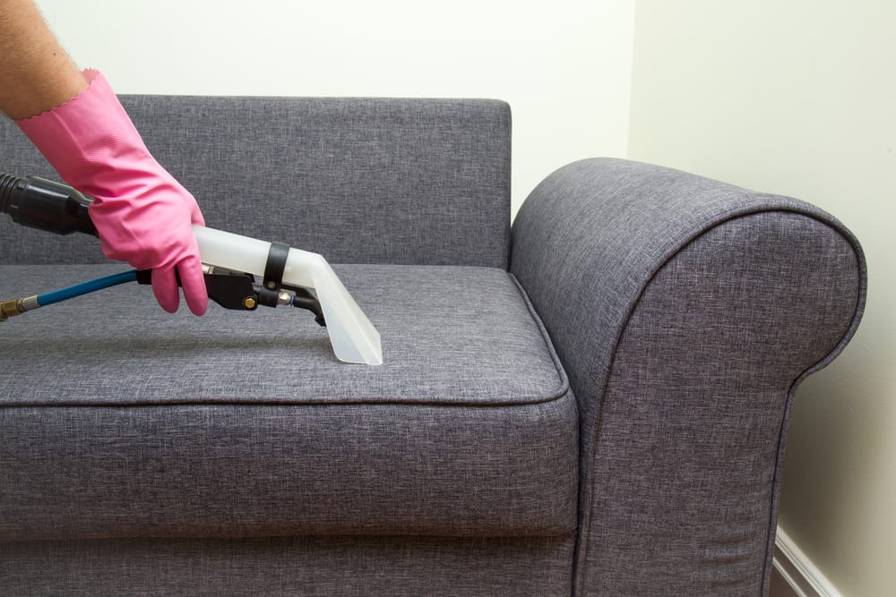 a person vacuuming a couch