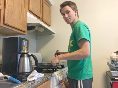 a young man college student cooking in a kitchen