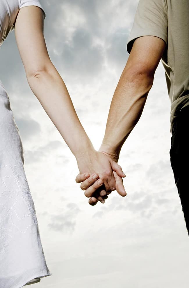 a man and woman holding hands with the sky in the background