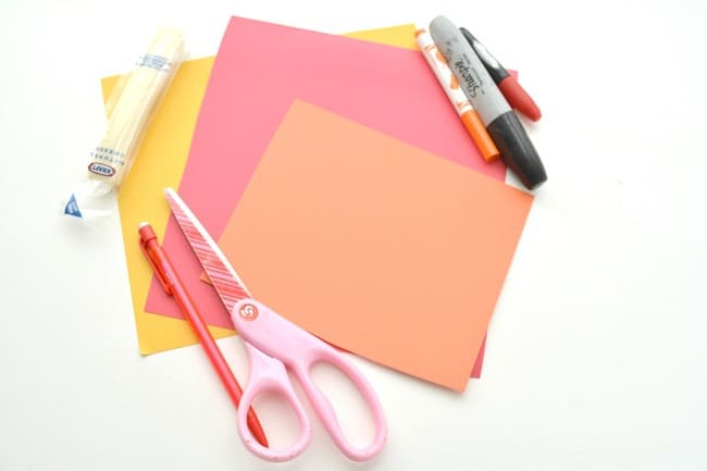 yellow, red, orange cardstock,  scissors, a pencil, a glue stick, cheese stick and markers on a white background