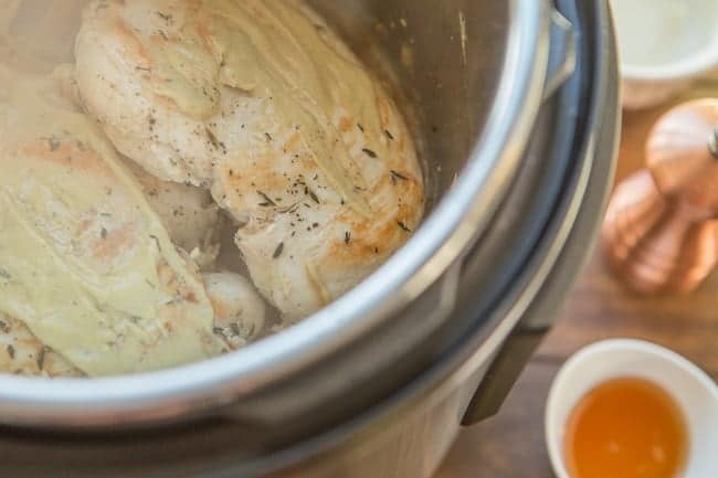 chicken in an instant pot next to a bowl of honey