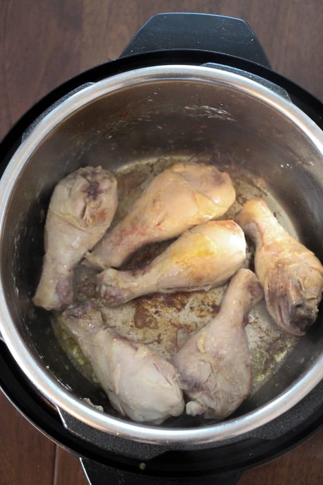 chicken legs being browned in oil in an instant pot