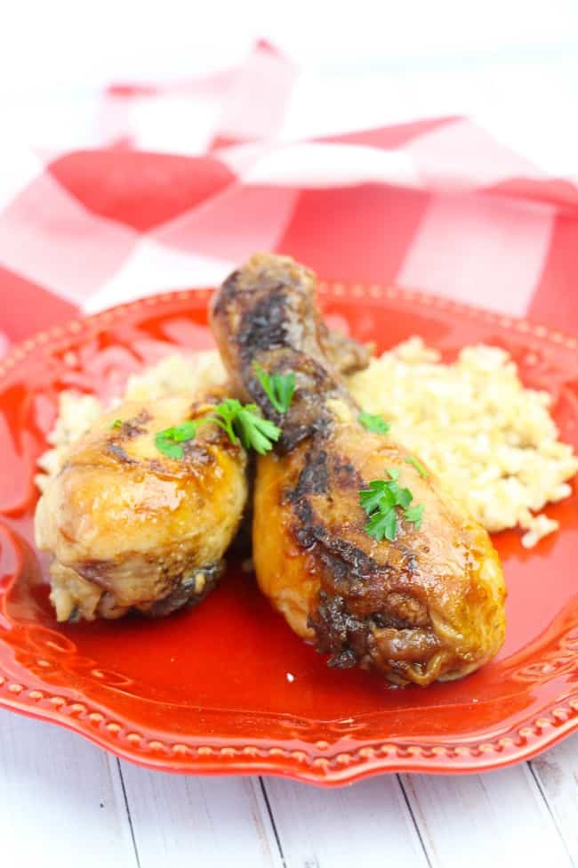 apple maple chicken legs and rice on a red plate on a red and white checkered cloth