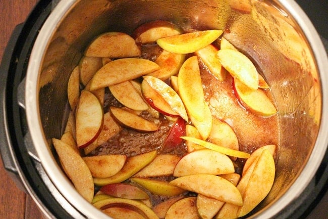butter and sliced apples coated with brown sugar and cinnamon in an instant pot on a brown table