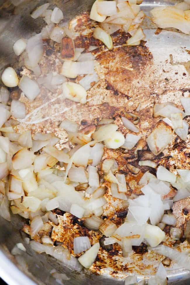 olive oil, chopped onions and garlic being cooked in an instant pot